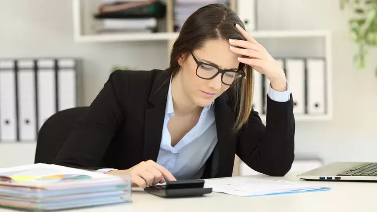 Antreprenoare cu calculatorul și documentele pe birou, verificând dacă firmele ei sunt întreprinderi legate